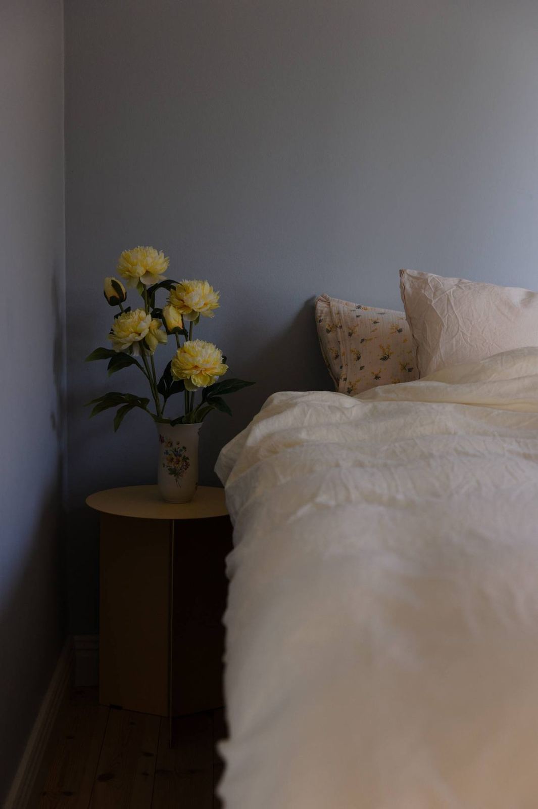 Soft blue bedroom with cream linen and yellow peonies