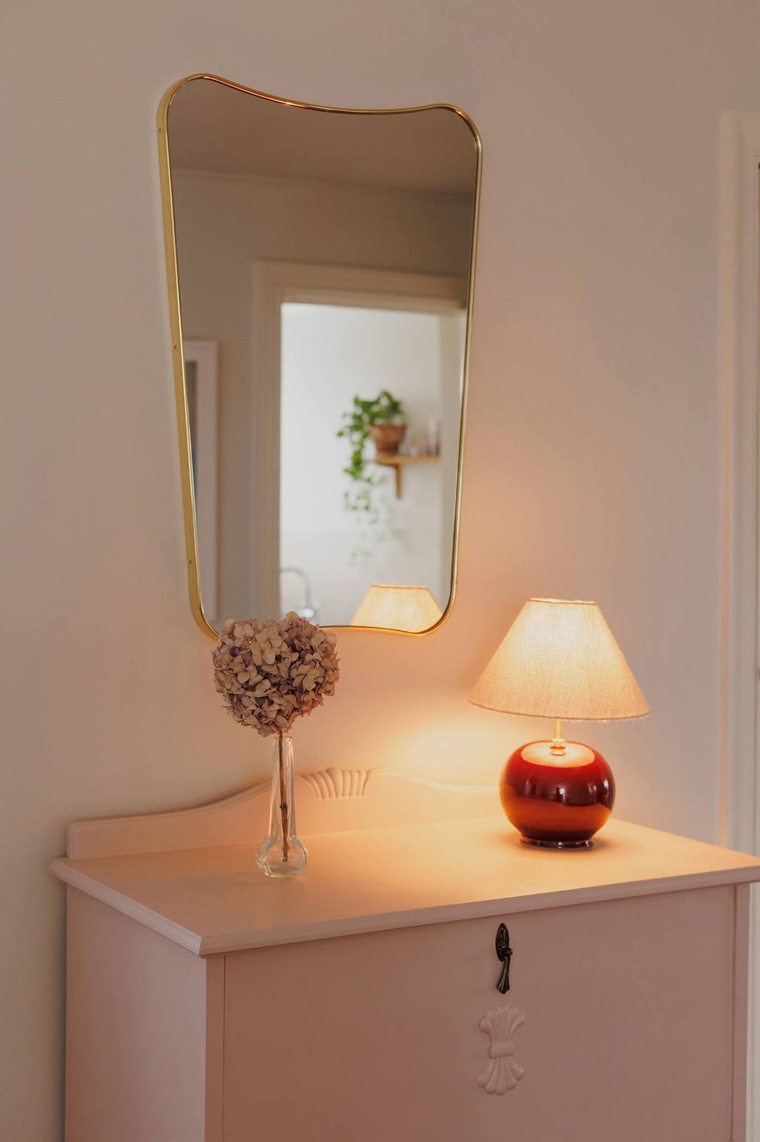 Upstairs hallway with brass mirror, glowing lamp and dried hydrangea