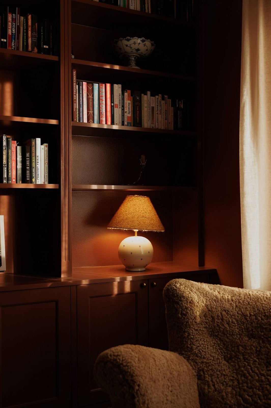 Library corner with classical bust, warm lamp and built-in shelves