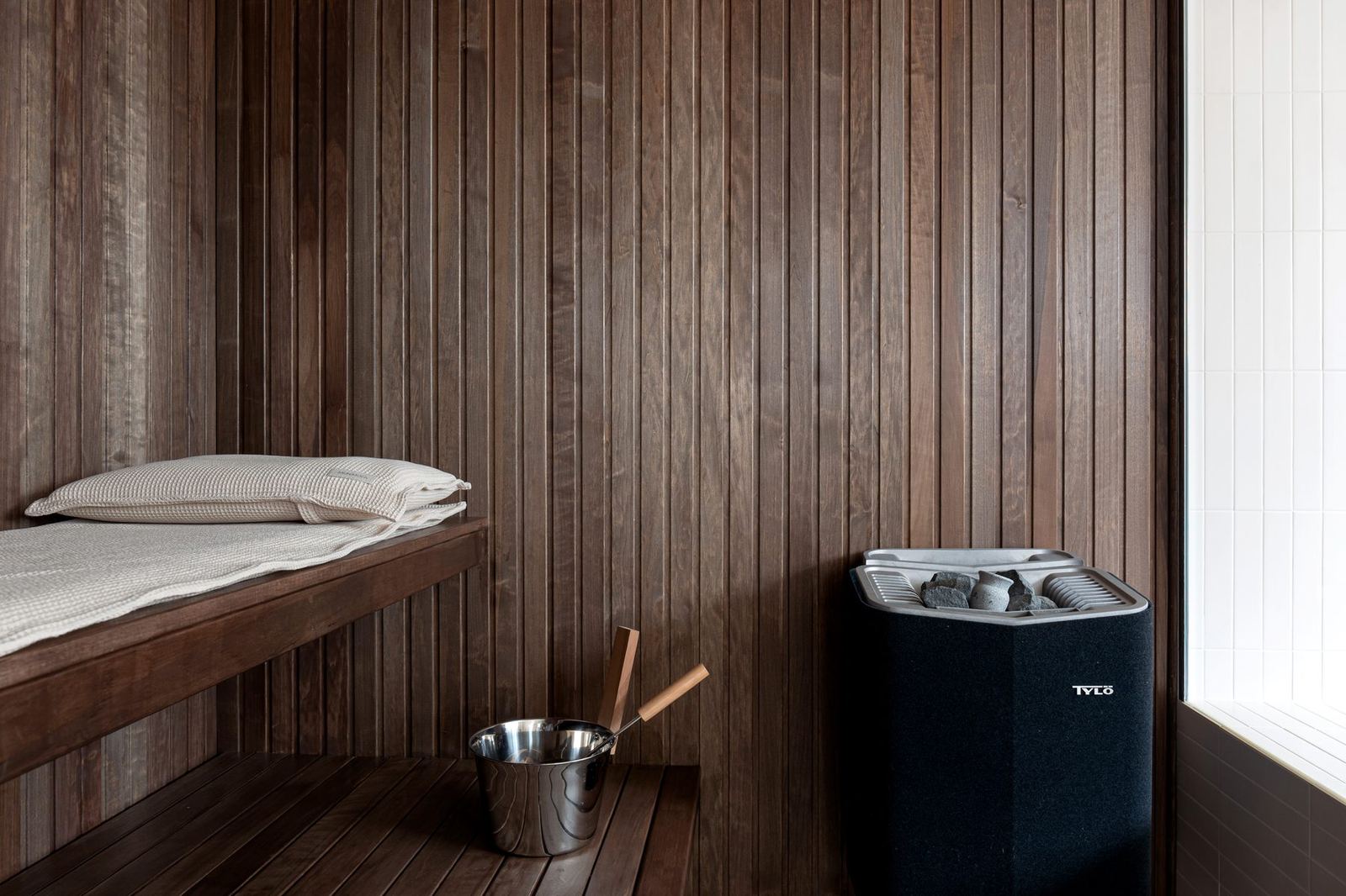 Dark-wood sauna with Tylö heater and rolled towels