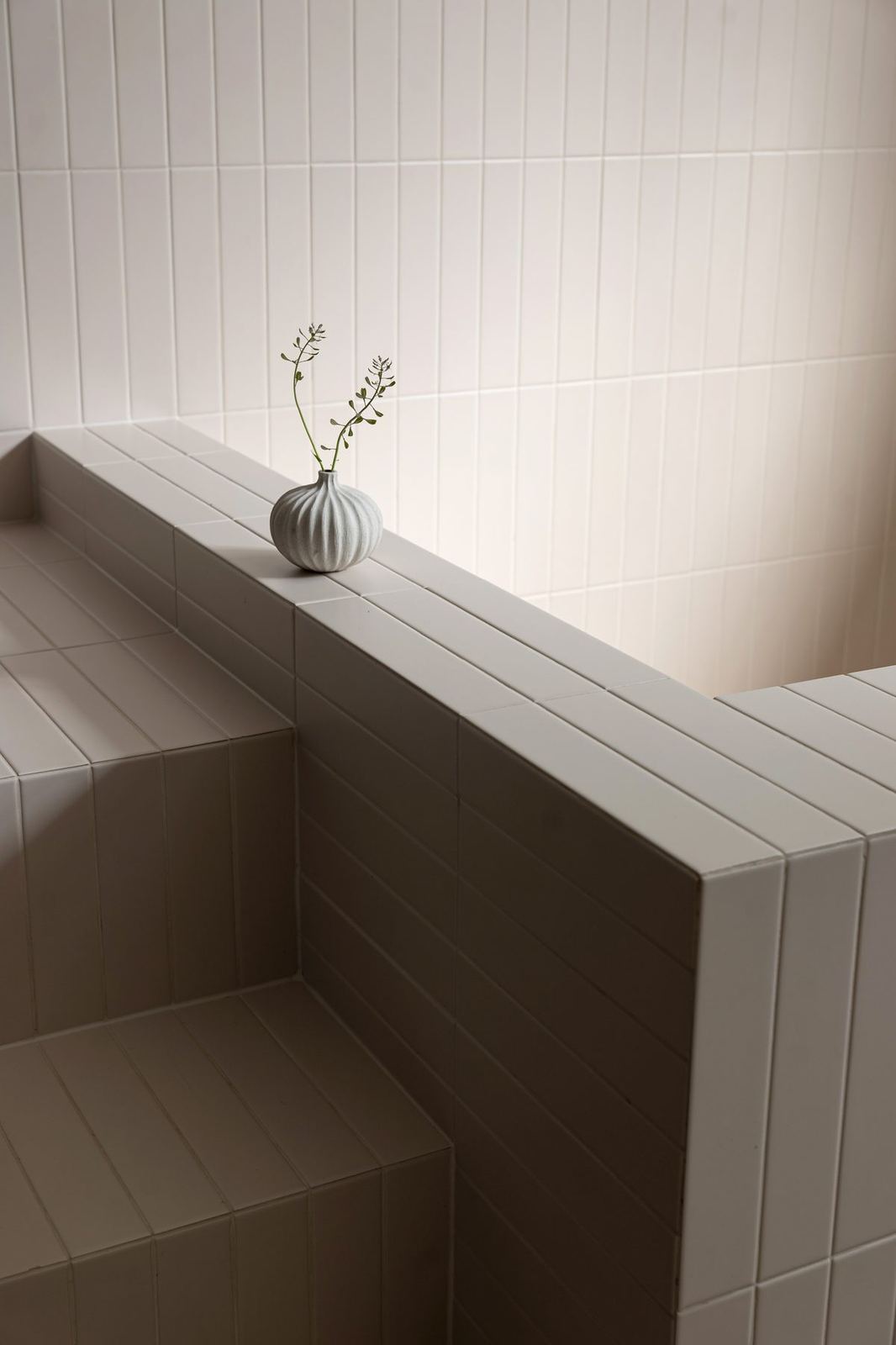 White-tiled spa with a single bud vase on the tiled bench