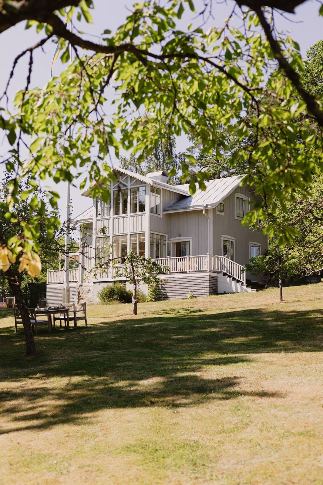 The villa in summer, with a table laid under the trees on the lawn